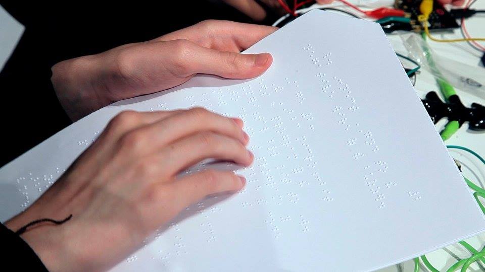 young person with visual impairment reading programming instruction in braille