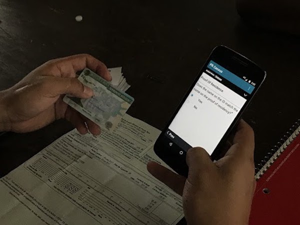 GiveDirectly field officer enters information from an ID into the TaroWorks app.