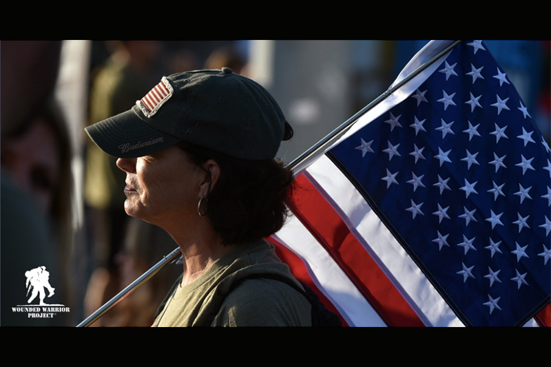 Woman carrying the American flag, with Wounded Warrior Project logo