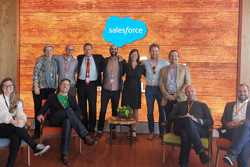 Group of men and women in front of Salesforce logo