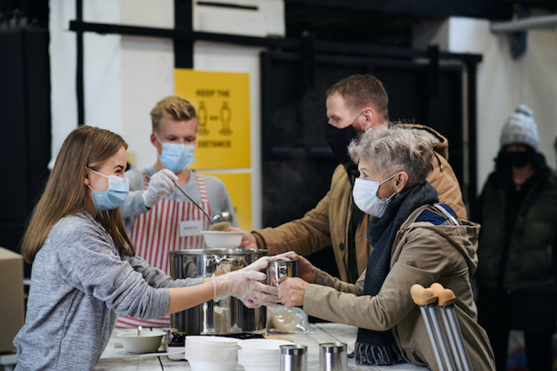 Volunteers wearing masks and serving hot soup at food bank
