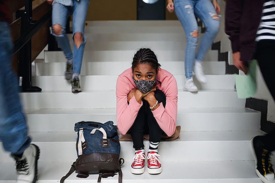 Young girl wearing a mask while sitting on steps