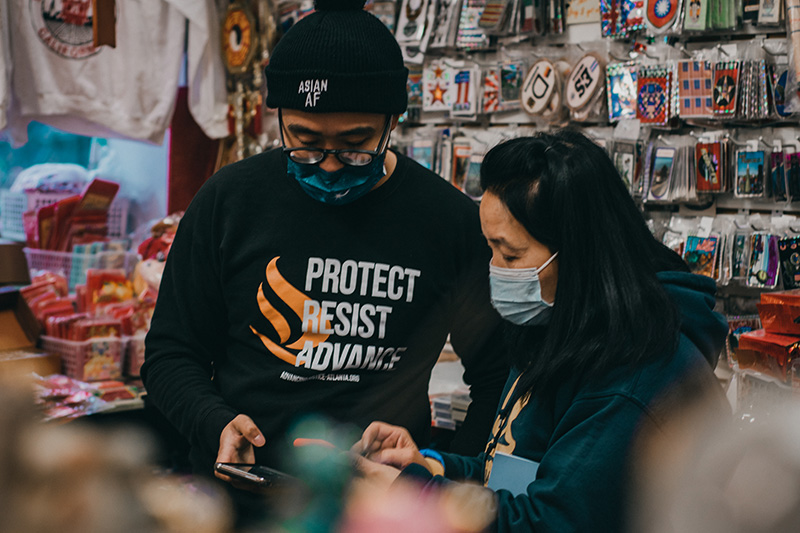 Man and woman looking at phones while wearing masks