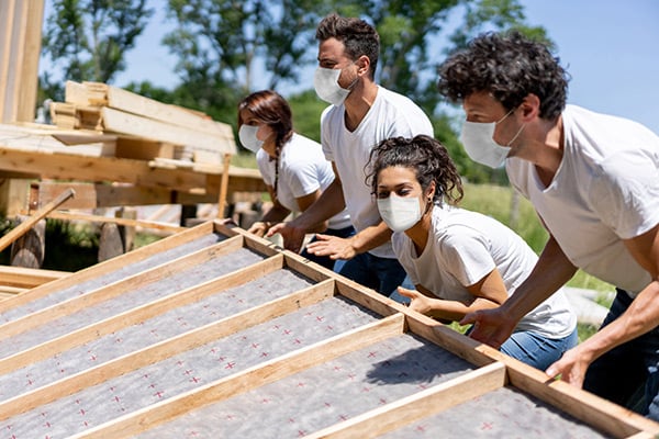 Volunteers building a house for charity while wearing a facemask during the COVID-19 pandemic