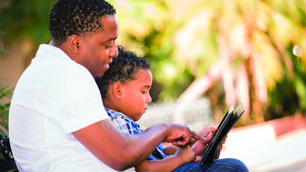 Man and child sitting down looking at a tablet