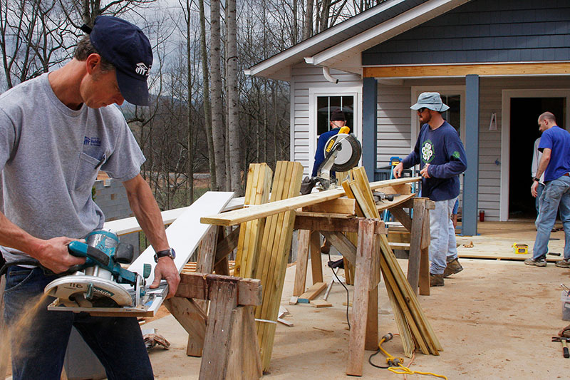 Volunteers cutting wood for a new home