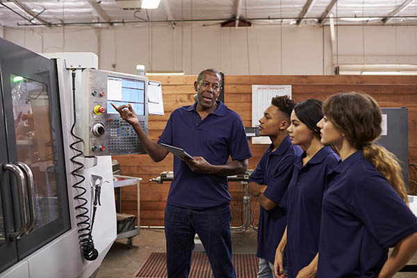 Man teaching group of people how to work a machine