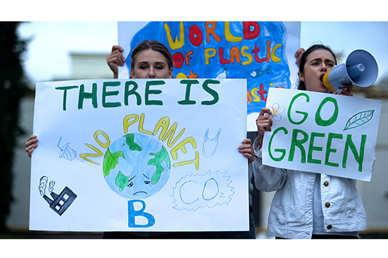 Two young protesters with signs demanding climate action.