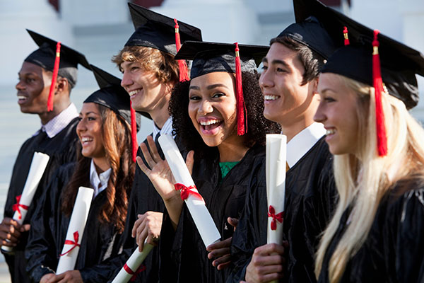 Students smiling while wearing graduation caps and gowns