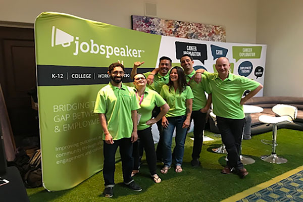 People posing and smiling in front of a Jobspeaker banner