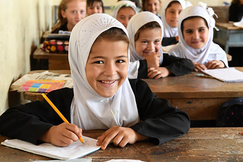 School children sitting at desks smiling