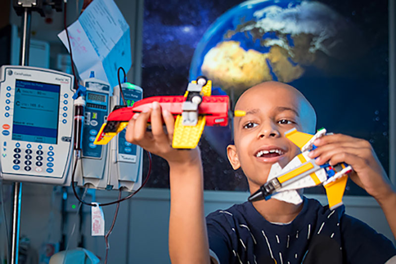 Child playing with toy spaceships in a hospital room