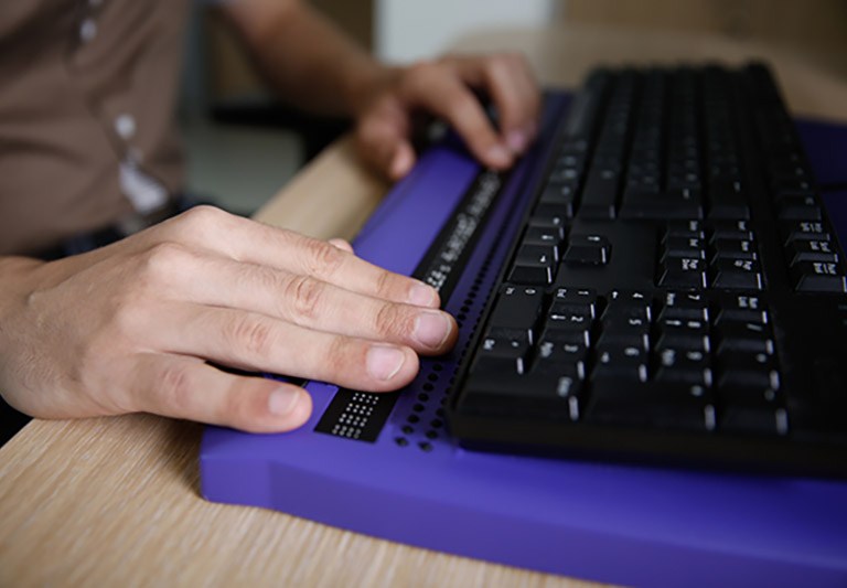 Blind person using computer with braille computer display stock photo