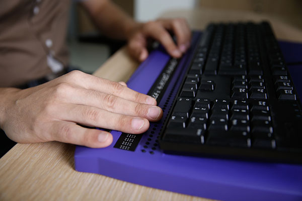 Blind person using computer with braille computer display stock photo