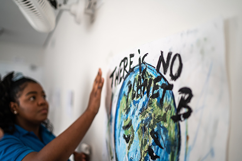 Student looking at a poster of earth with the words “There is no planet B”