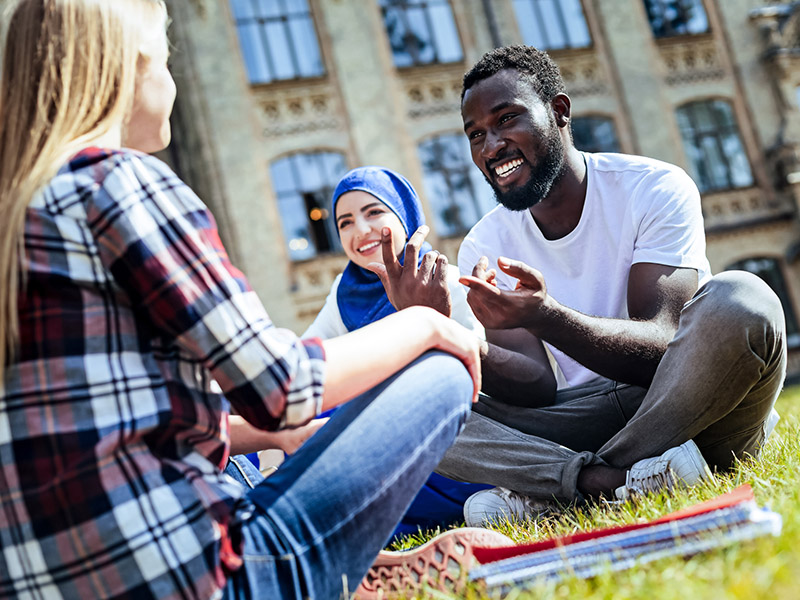 Students sitting in a university quad smiling and talking